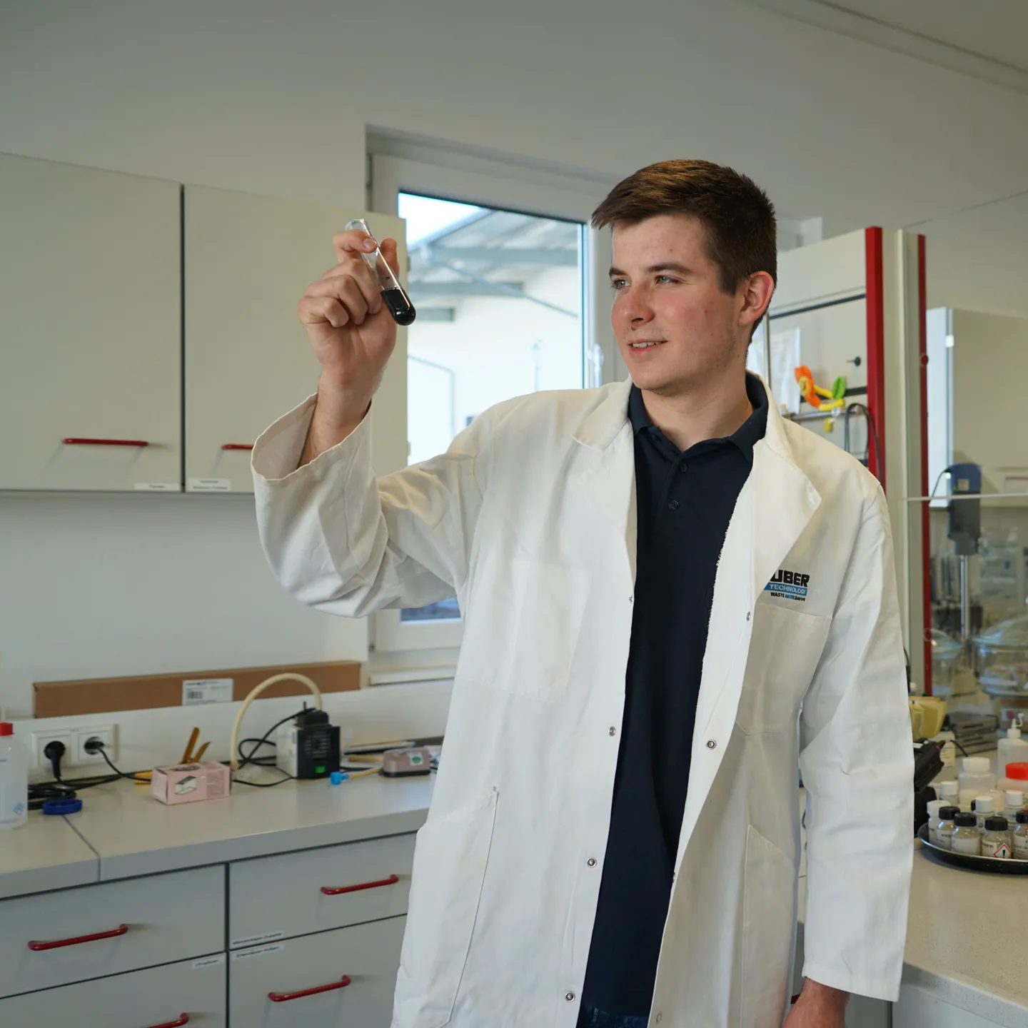 Johannes Kratzer im Laborkittel betrachtet ein Reagenzglas im Labor