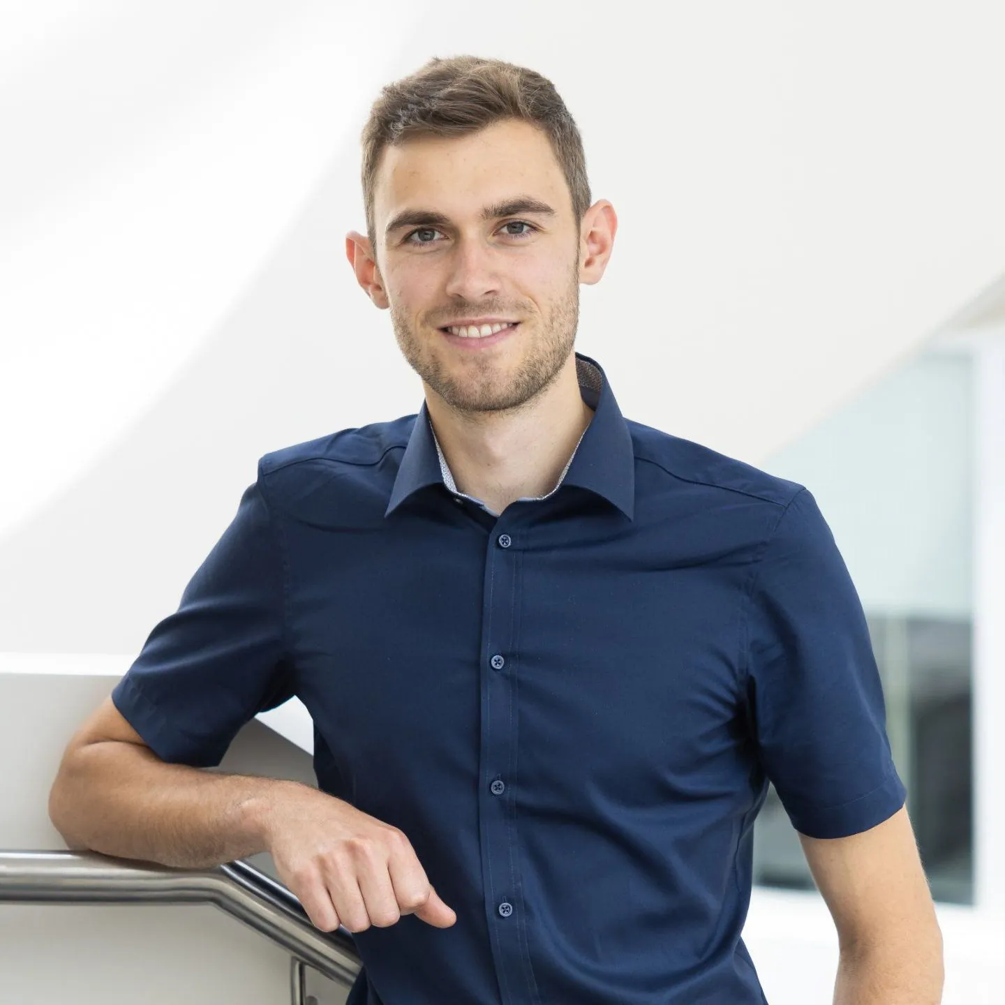 Lukas Wenger lehnt lächelnd an einem Treppengeländer